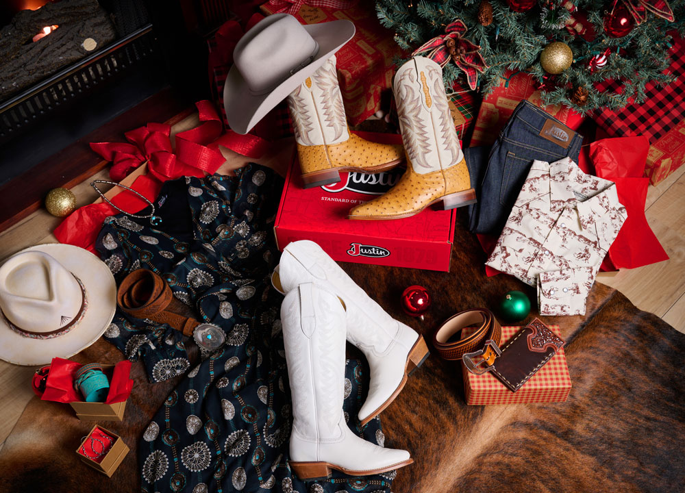 Pasco 13” tan smooth ostrich boots, a hat, cream snap shirt, unwashed blue straight-leg jeans, and Evelyn Vintage Ivory 15” cowhide boots, under a Christmas tree.