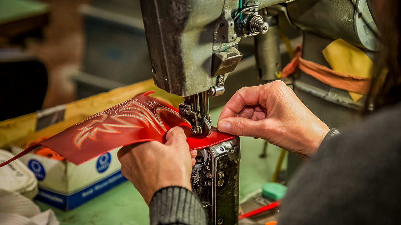 Person embroiders leather for Justin boot 