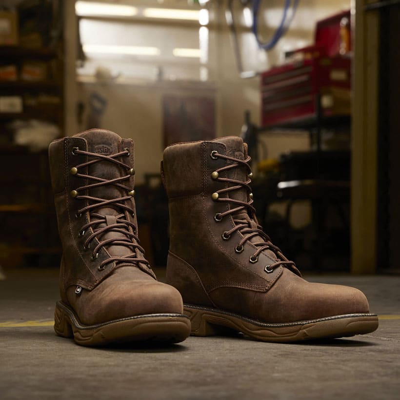 Men’s Rush 8” Lace Up Nano Compt Toe work boot in brown posed in a work space on concrete. 