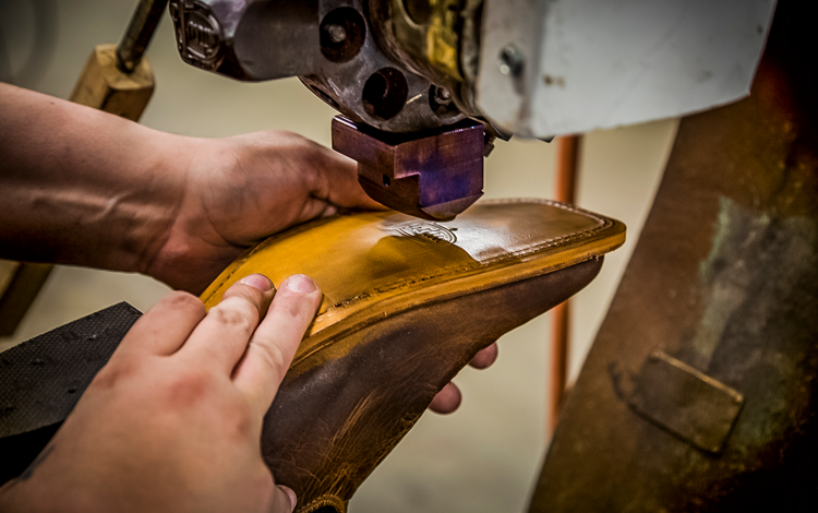 Man uses machine on sole of Justin boot