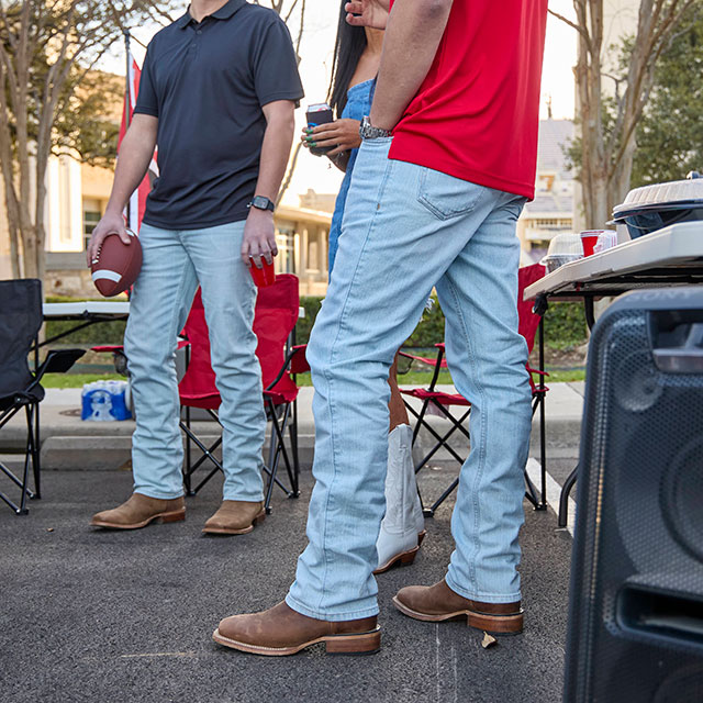 Two men wearing Justin Original Straight Leg Men's Jeans in Ultralight wash stand by a tailgate of a truck. Shop Justin Original Straight Leg Men's Jeans