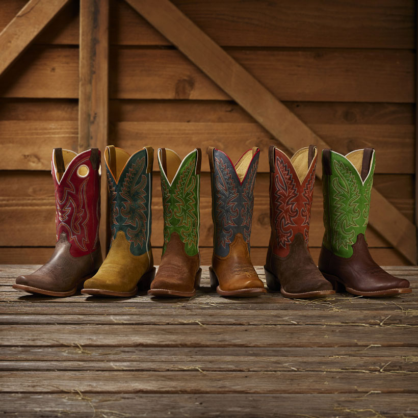 Ante Up 13” Western Boot, Show Off 13” Wetsern Boot. And Jimmy 13” Western boot in different shades of red, blue, green and brown, posed against a wooden wall.