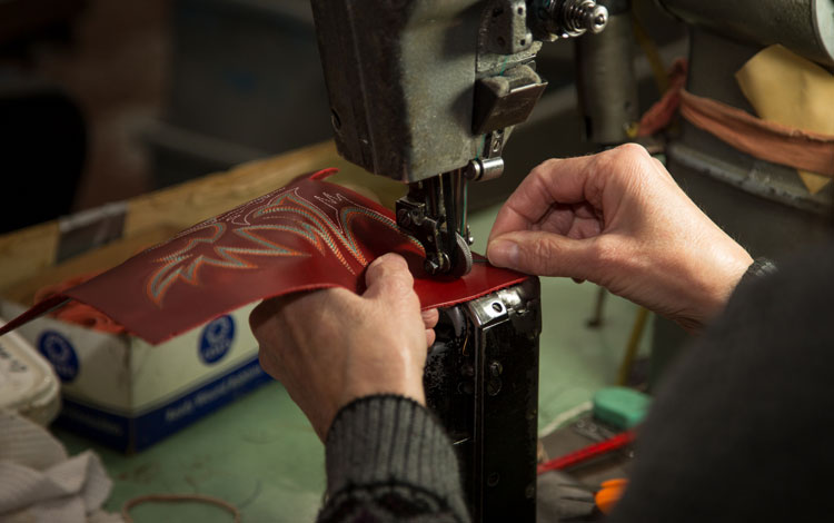 Person embroidering leather for a boot