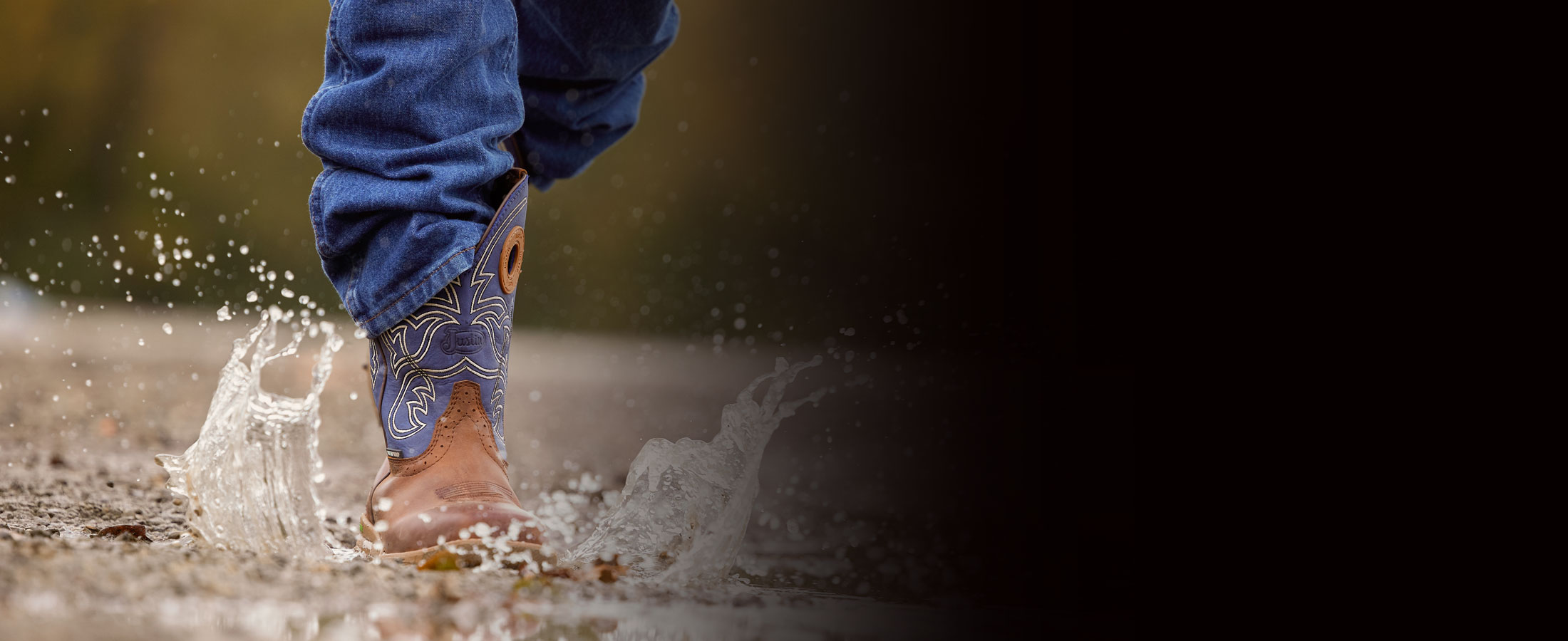 A man wearing Justin Waterproof work boots while walking through a puddle.