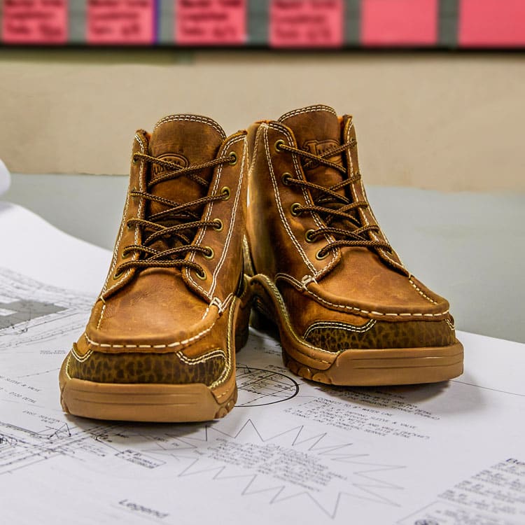 Corbett 5” waterproof work lace-up boots posed on a table at a construction office. 