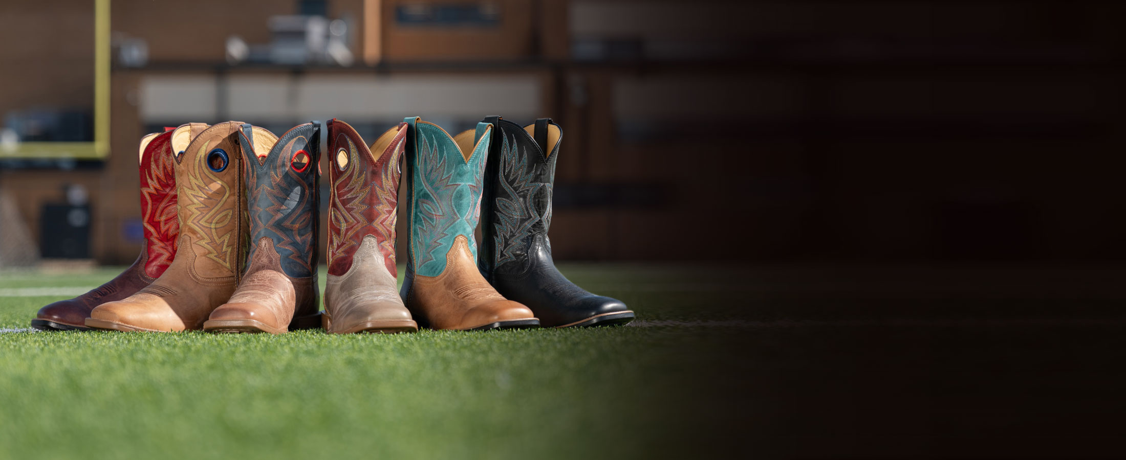 Zeke 11" Western boot in Mohogany, Pickett 11" Western boot in light oak (tan), Pickett 11" Western boot in peanut (brown), Pickett 11" Western boot in Griege (grey), Zeke 11" Western boot in peanut (brown)and Zeke 11" Western boot in peanut (black) on a turf field.