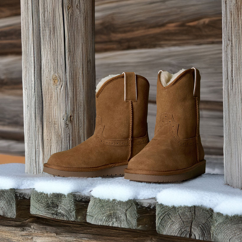 Heidi 8" Suede Shearling boots in chestnut tan posed on a porch in the snow.