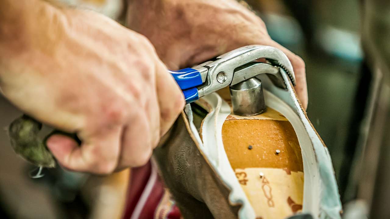 Man uses tool on sole of Justin boot