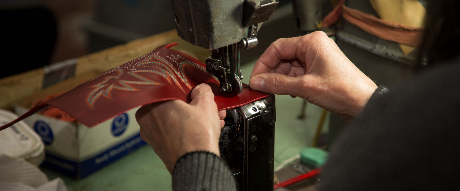 Person embroidering leather for a boot