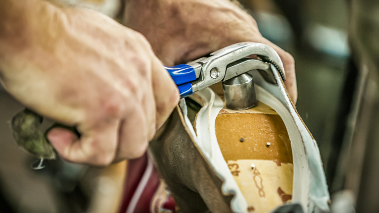 Man uses tool on sole of Justin boot