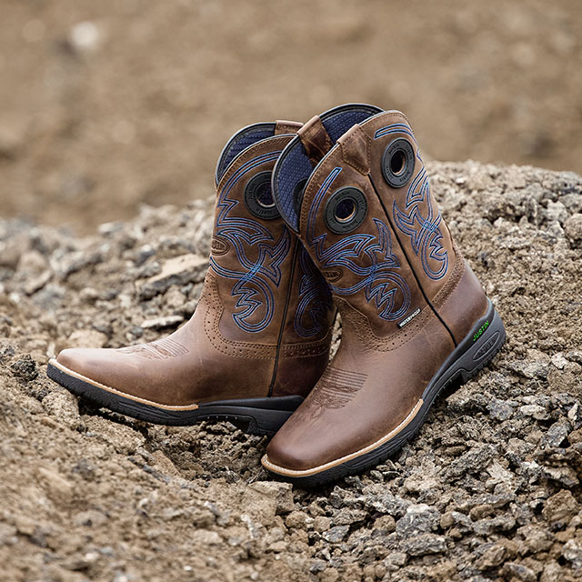 The Justin Commander with NiTread technology 11-inch Waterproof Nano Composite Toe Boots in Toffee (brown) sitting on the rocky ground. Shop Commander.