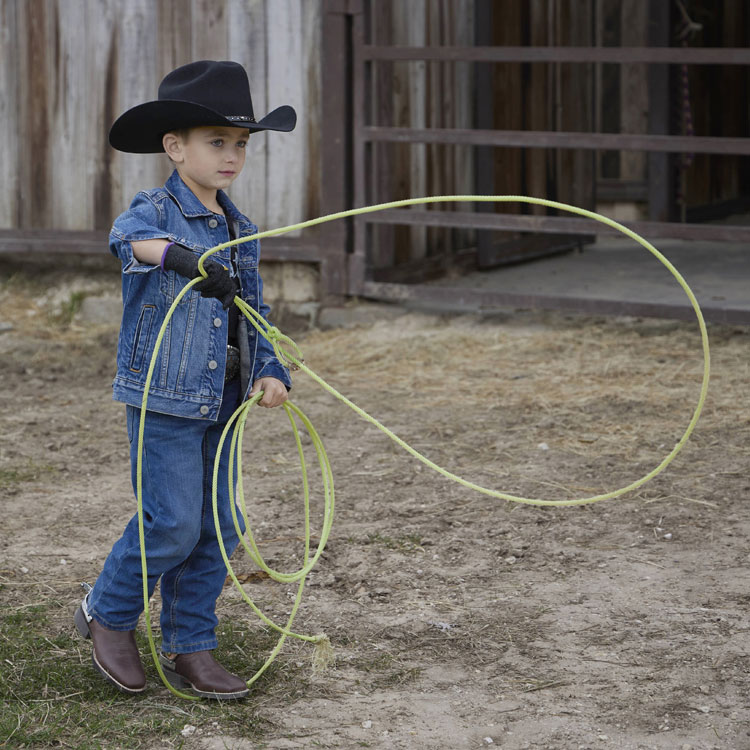 Kids’ Bowline Junior cowboy boots in brown, worn by a little boy holding a rope. 