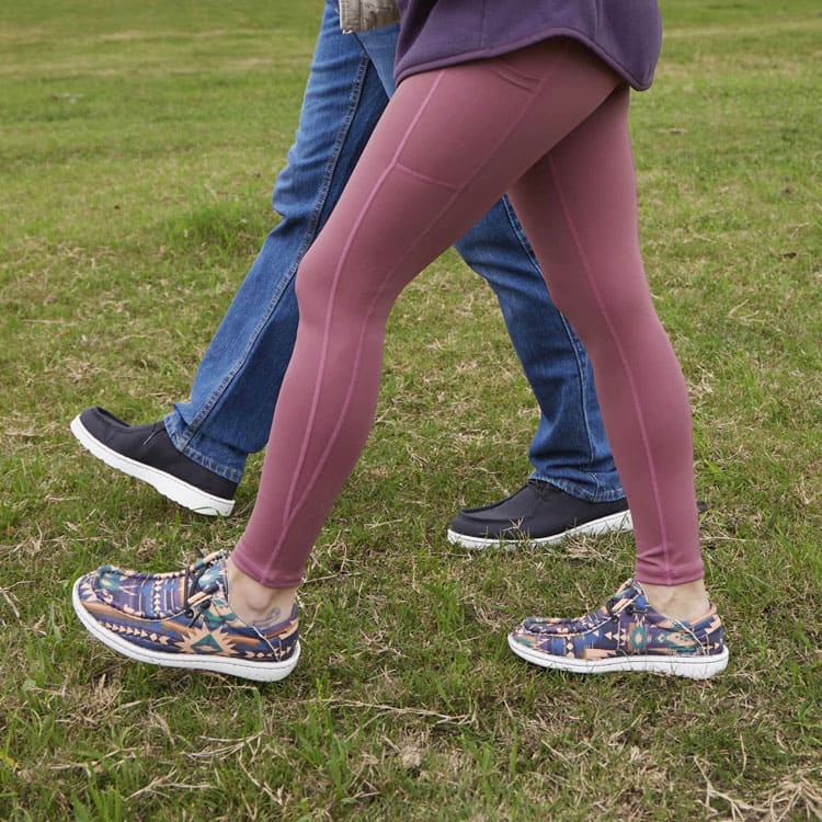 A woman wearing women’s conceal carry leggings in mauve walking with a man. 