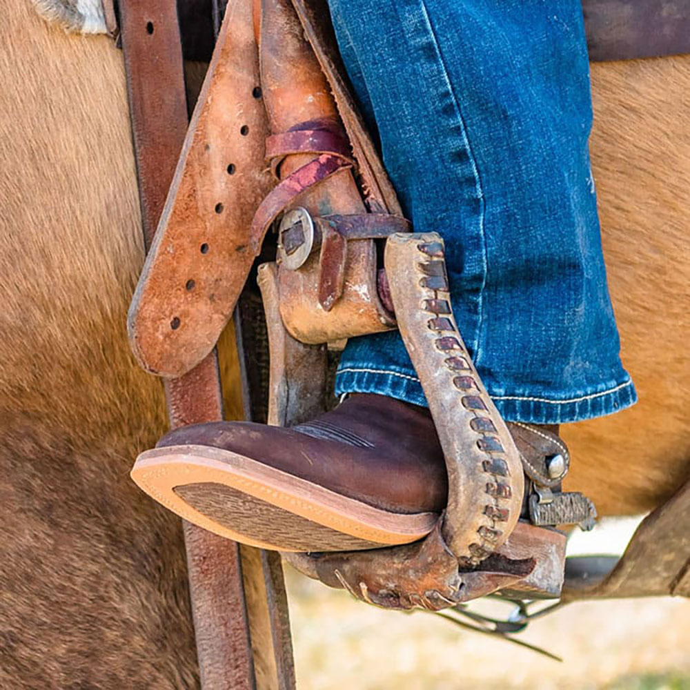 Close up of horse and brown boot in stirrup 