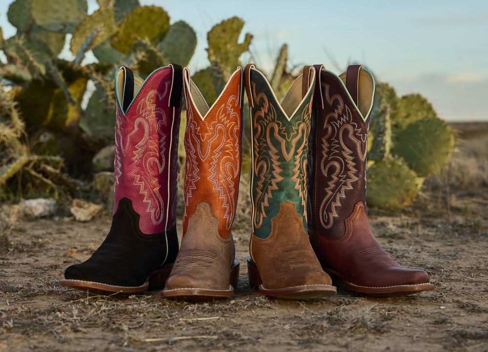 A group of Justin women’s Frontier western boots displayed in a desert.