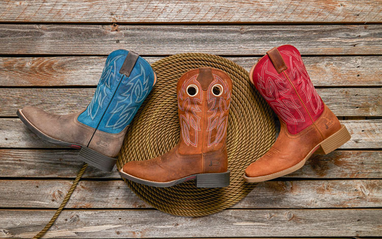 Three Western boots lying down on a rope and wood.