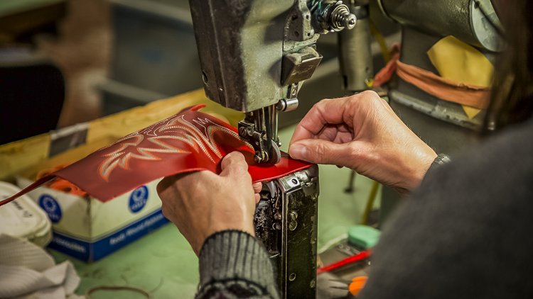 Person embroiders leather for Justin boot 