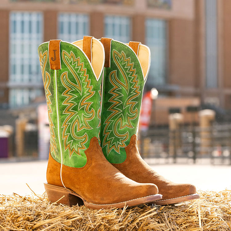 Men’s Jimmy 13” Western boots in green and tan, posed on a hay bale. Shop Jimmy