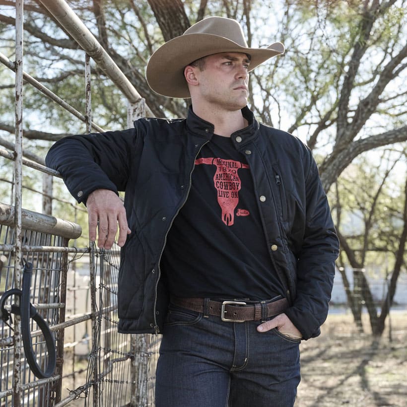 Men’s quilted jacket in black worn my a model also wearing a tan cowboy hat. 