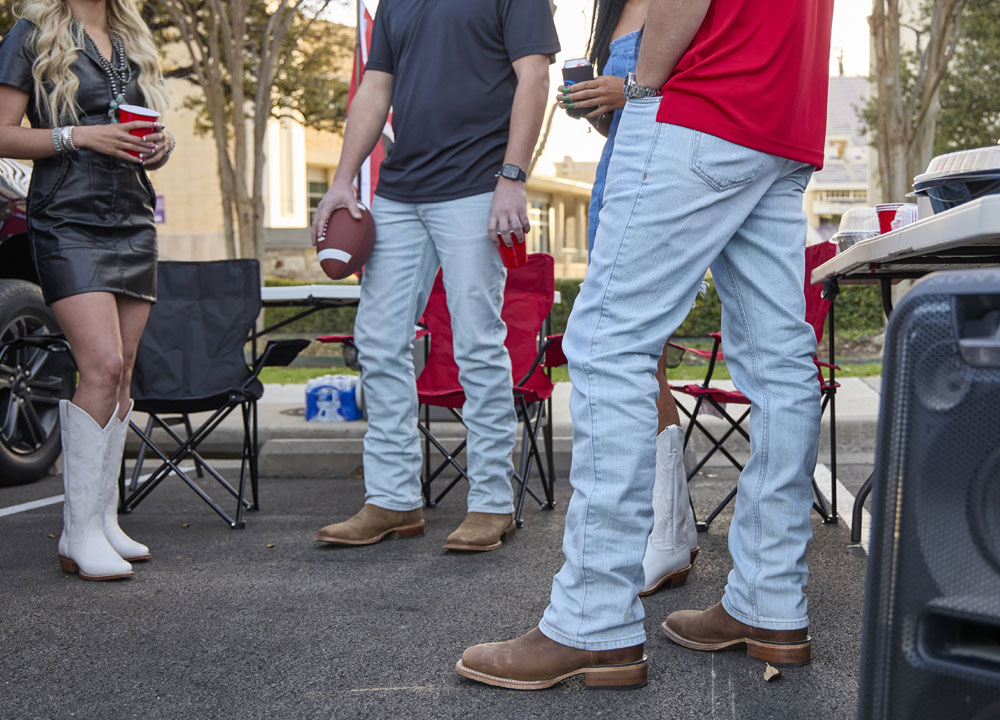 Two men wearing Justin Original Straight Leg Men's Jeans in Ultralight stand by the tailgate of a truck.