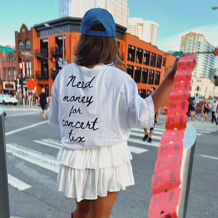 A woman wearing a white t-shirt and skirt holding red tickets.