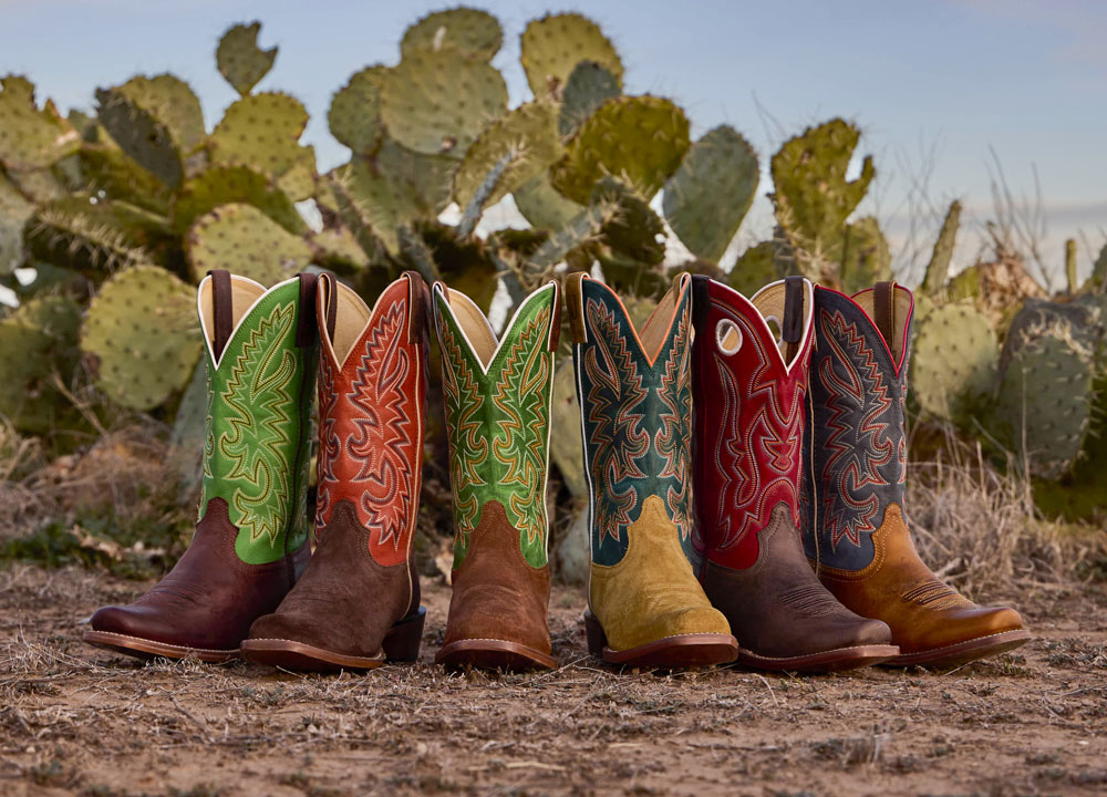 A group of Justin Men's Frontier Cutter toe boots in the desert.