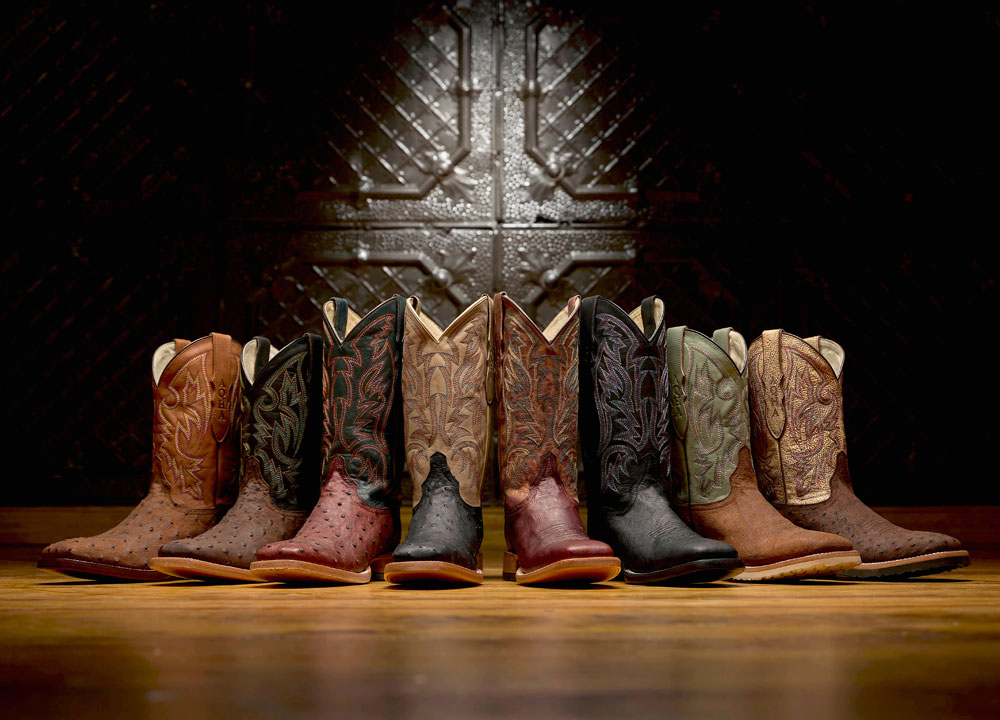 Three Bars Smooth Ostrich western boot in black, Three Bars Smooth Ostrich western boot in Brown, Doc bar Full Quill Ostrich western boot in brown, Doc bar Full Quill Ostrich western boot in black, King Full Quill Ostrich western boot in Brown posed against a black wall.