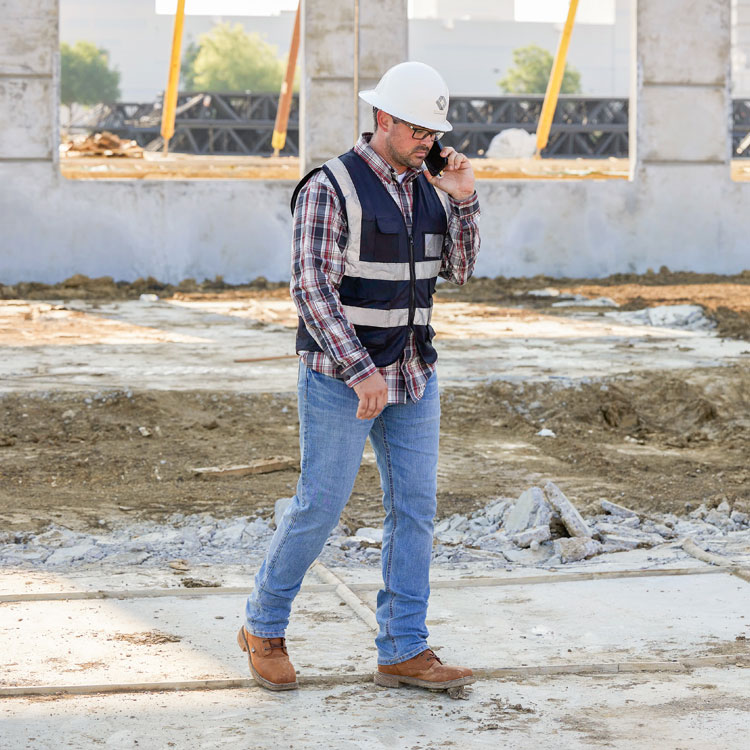 A construction worker wearing Justin 1879 Straight Leg Men's Jeans in Light Wash. Shop Justin 1879 Straight Leg Jeans.