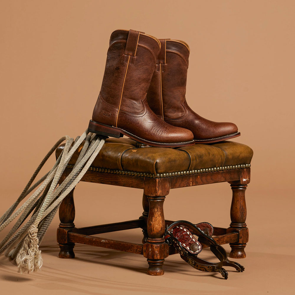 Justin Holland 10" women’s Roper in brown siting on a stool. Shop Holland