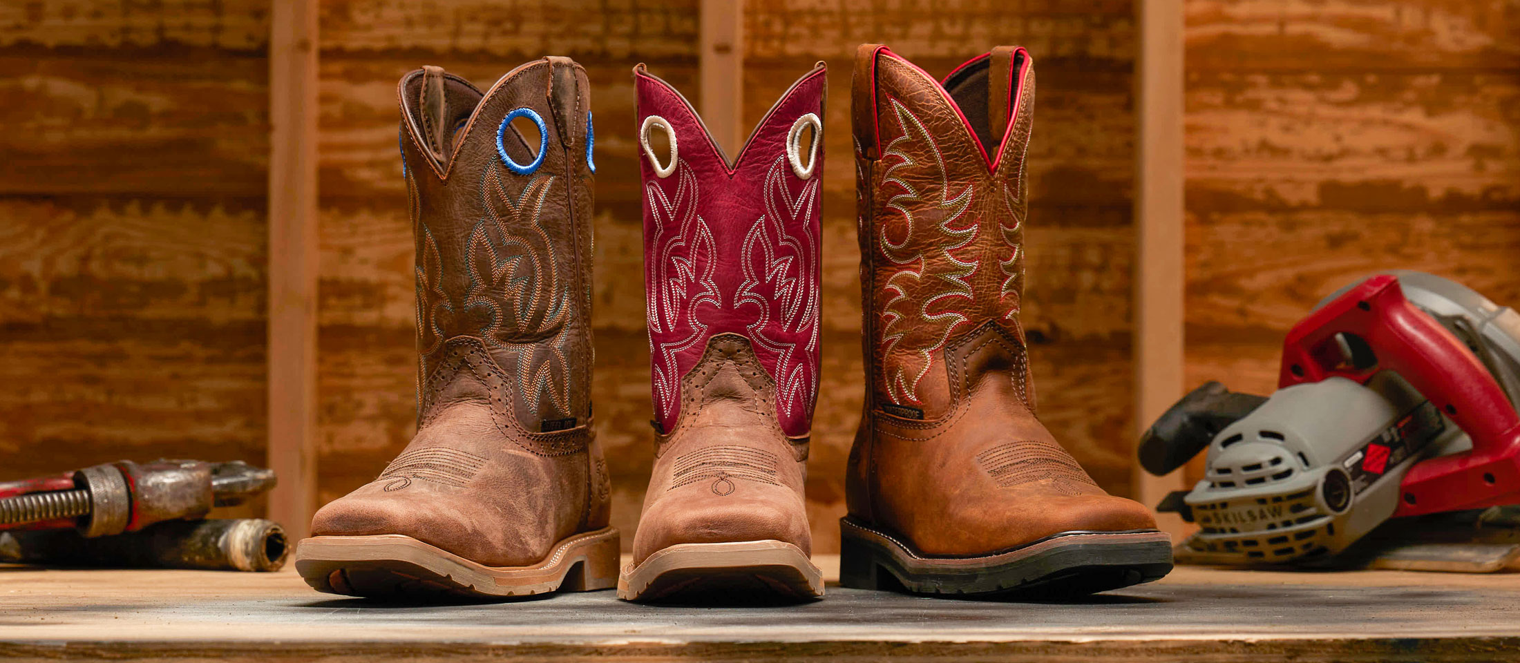 Three work boots facing the camera and placed with power tools.