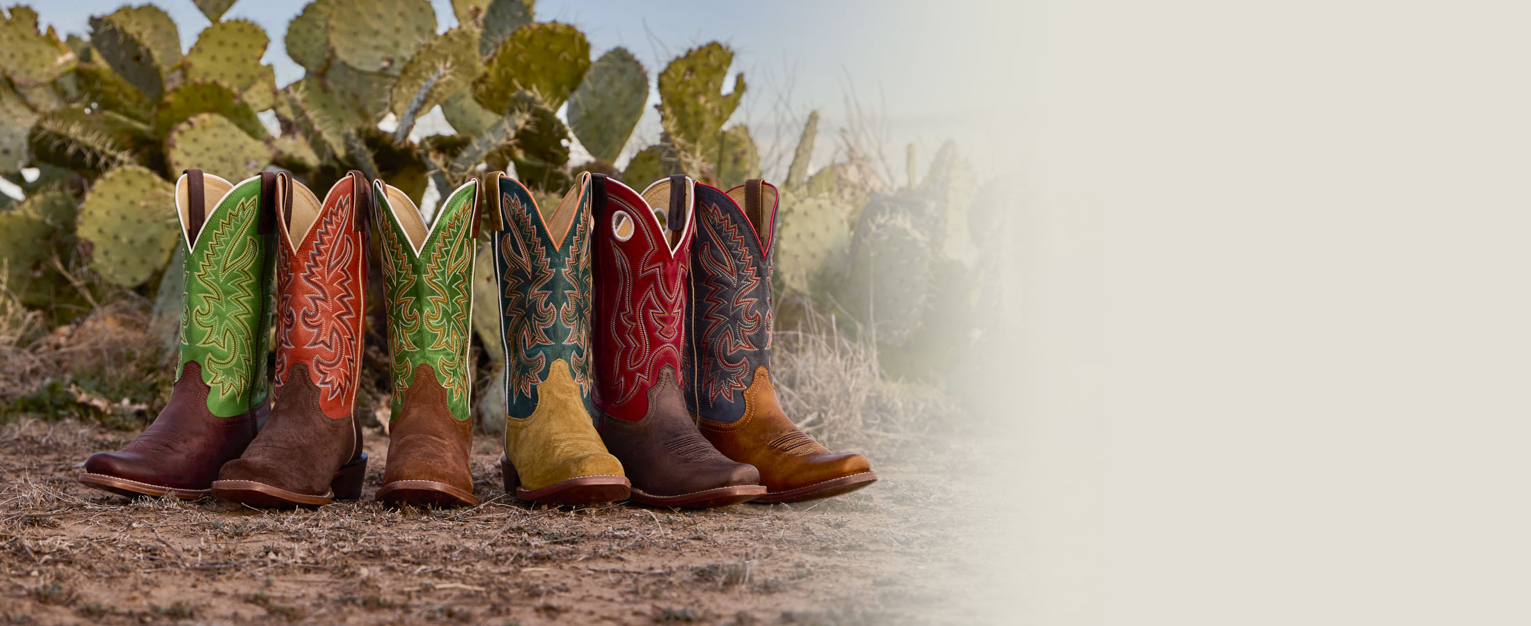 A group of Justin Men's Frontier Cutter toe boots in the desert.