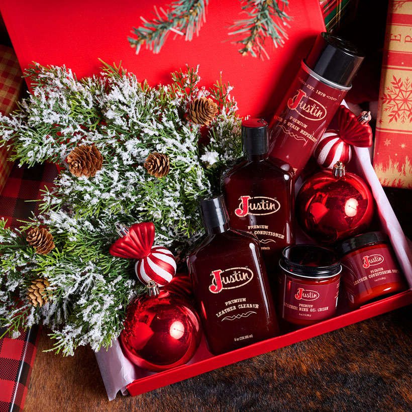 Bottles and jars of boot leather cleaner in a box surrounded by wrapped Christmas presents.