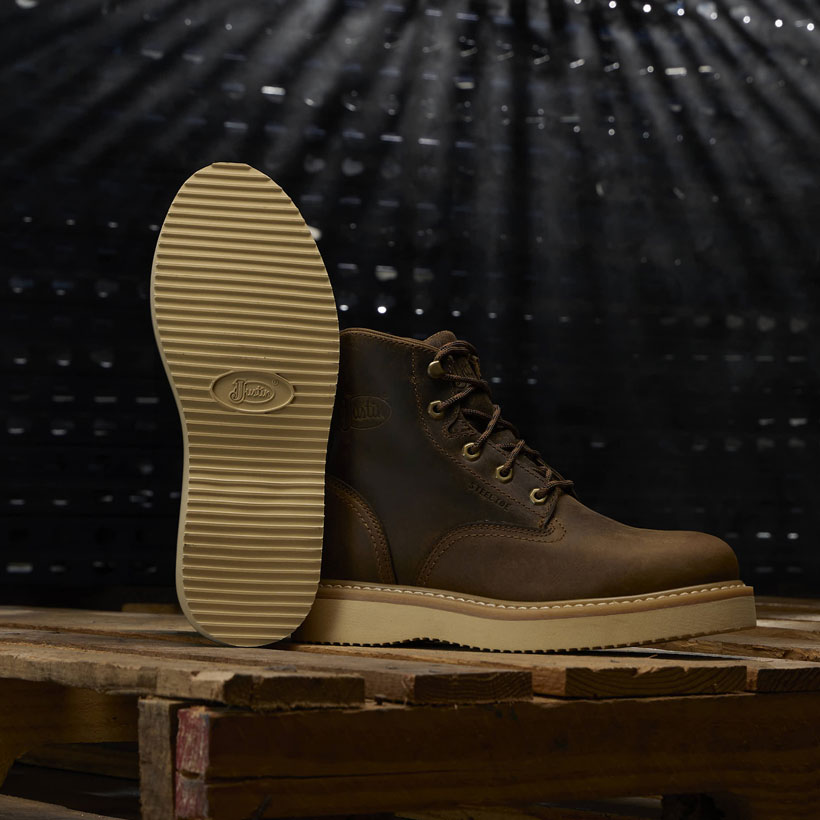 Men’s Maxwell 6" Lace Up in brown posed on a wood pallet in a dark room. 