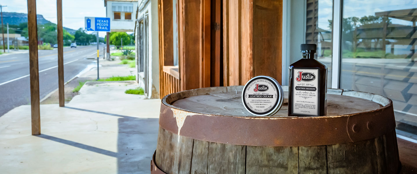 Justin leather care products sitting on a barrel.