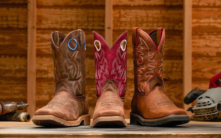 Three work boots facing the camera and placed with power tools.