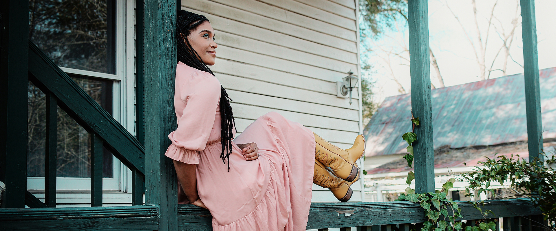 Cadance con vestido rosa y botas amarillas sentada en la barandilla fuera de la casa