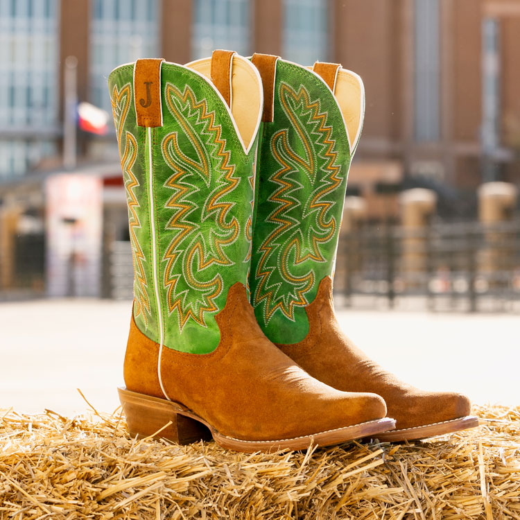 A pair of Justin Jimmy 13-inch Western boots in green and brown sitting on a pile of hay. Shop Jimmy