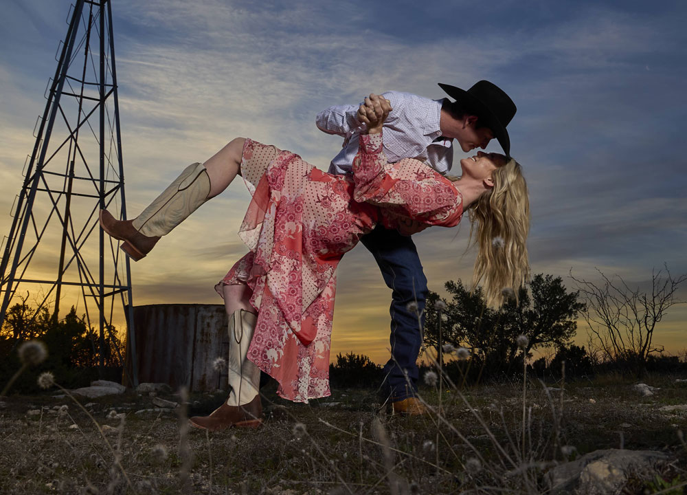 A woman wearing Justin Women’s Wrap Maxi Dress in red and a man wearing show off 13” western boot in tan. 