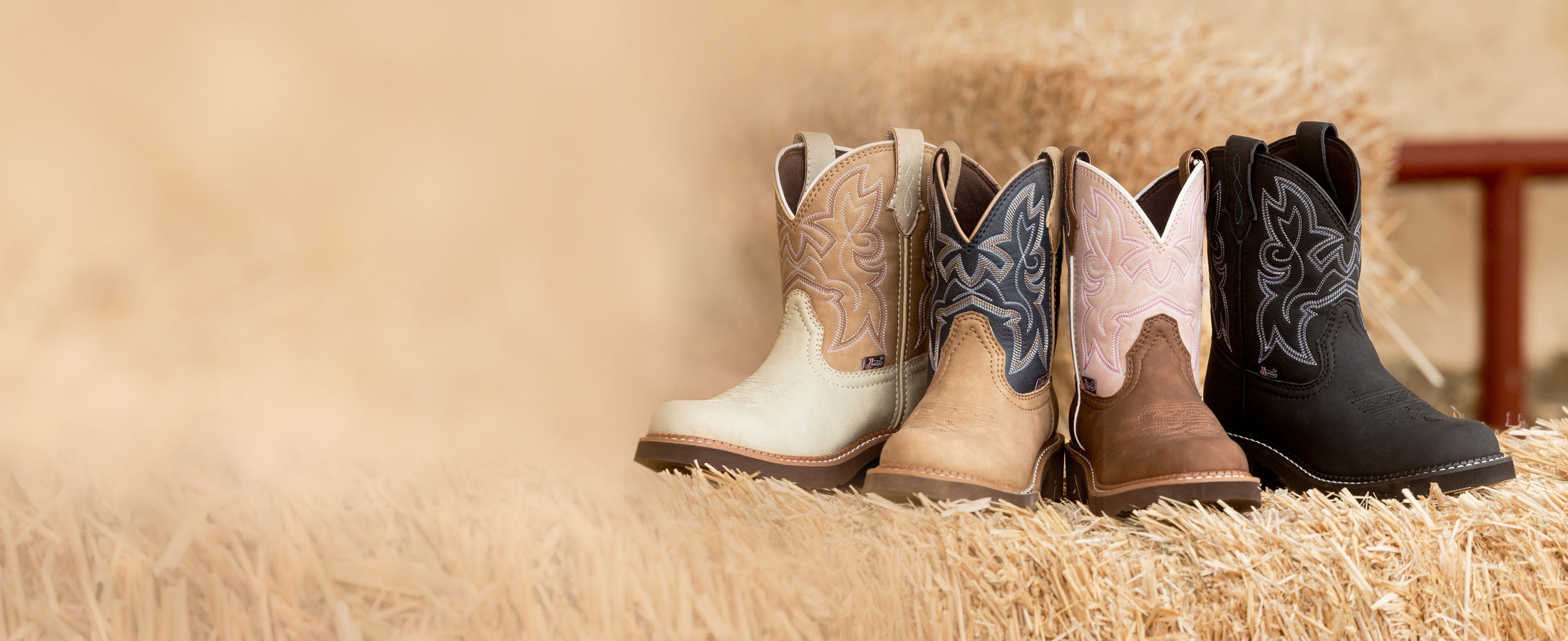 Kay 8” Western boots in brown and black posed on a hay bale at a cattle barn.