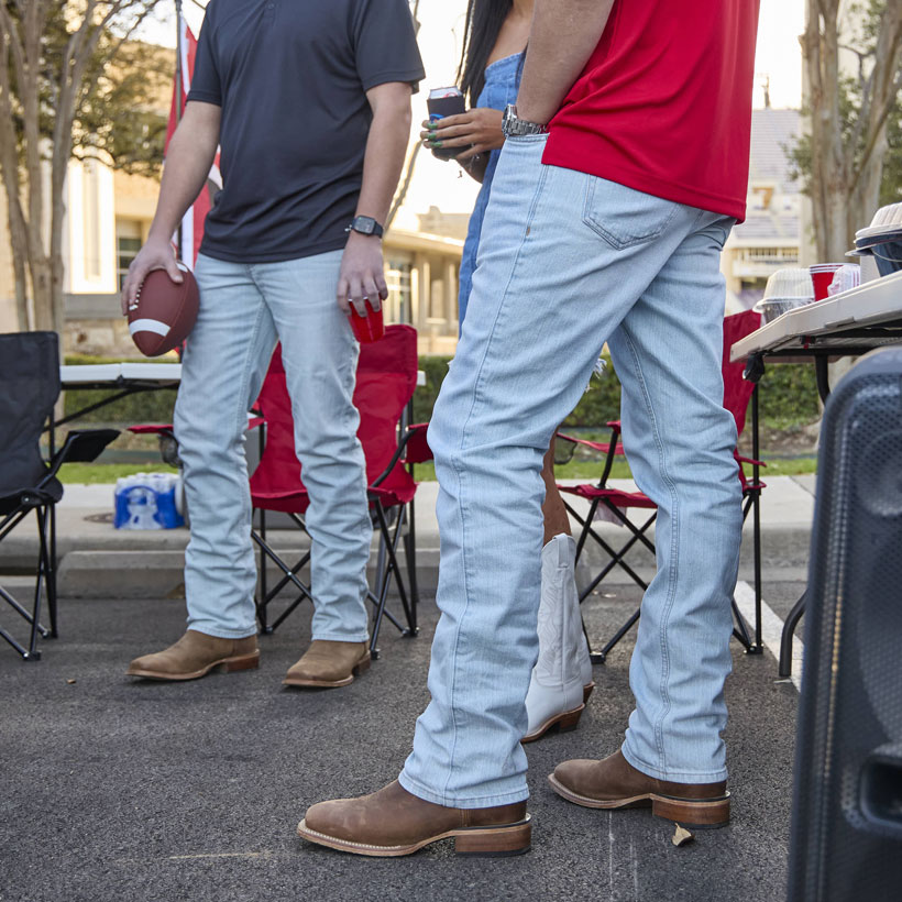 Two pairs of Original Straight Leg Men's jeans in the color ultra light blue worn boy two men at a football tailgate.