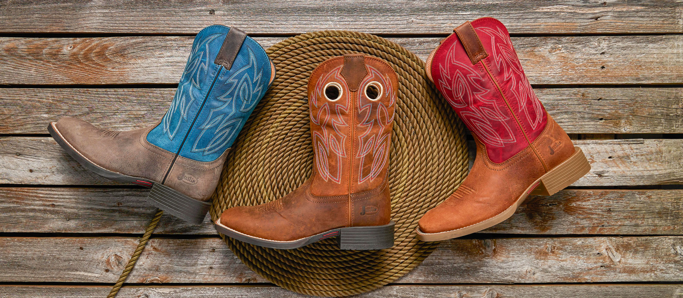 Three Western boots lying down on a rope and wood.