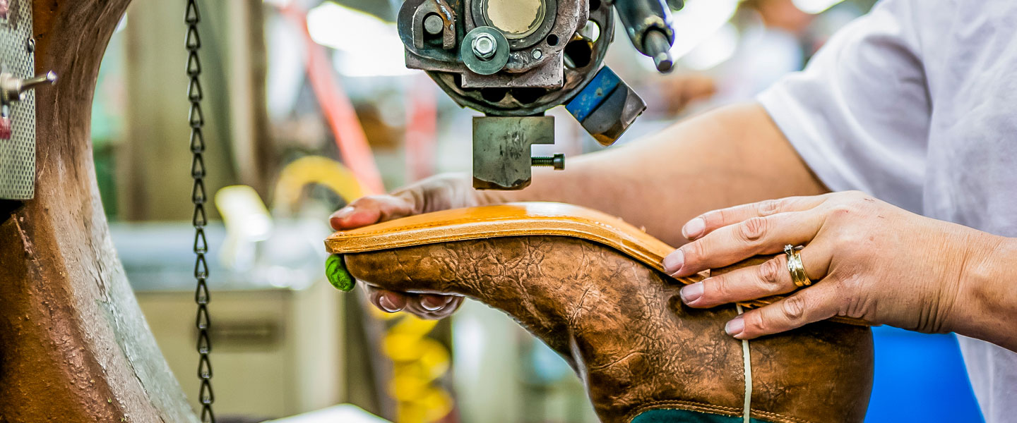 Worker attaching a leather sole to boot.